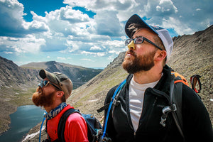 Two earth conscious explorers on a mountain wearing their biodegradable NÖZ sunscreen